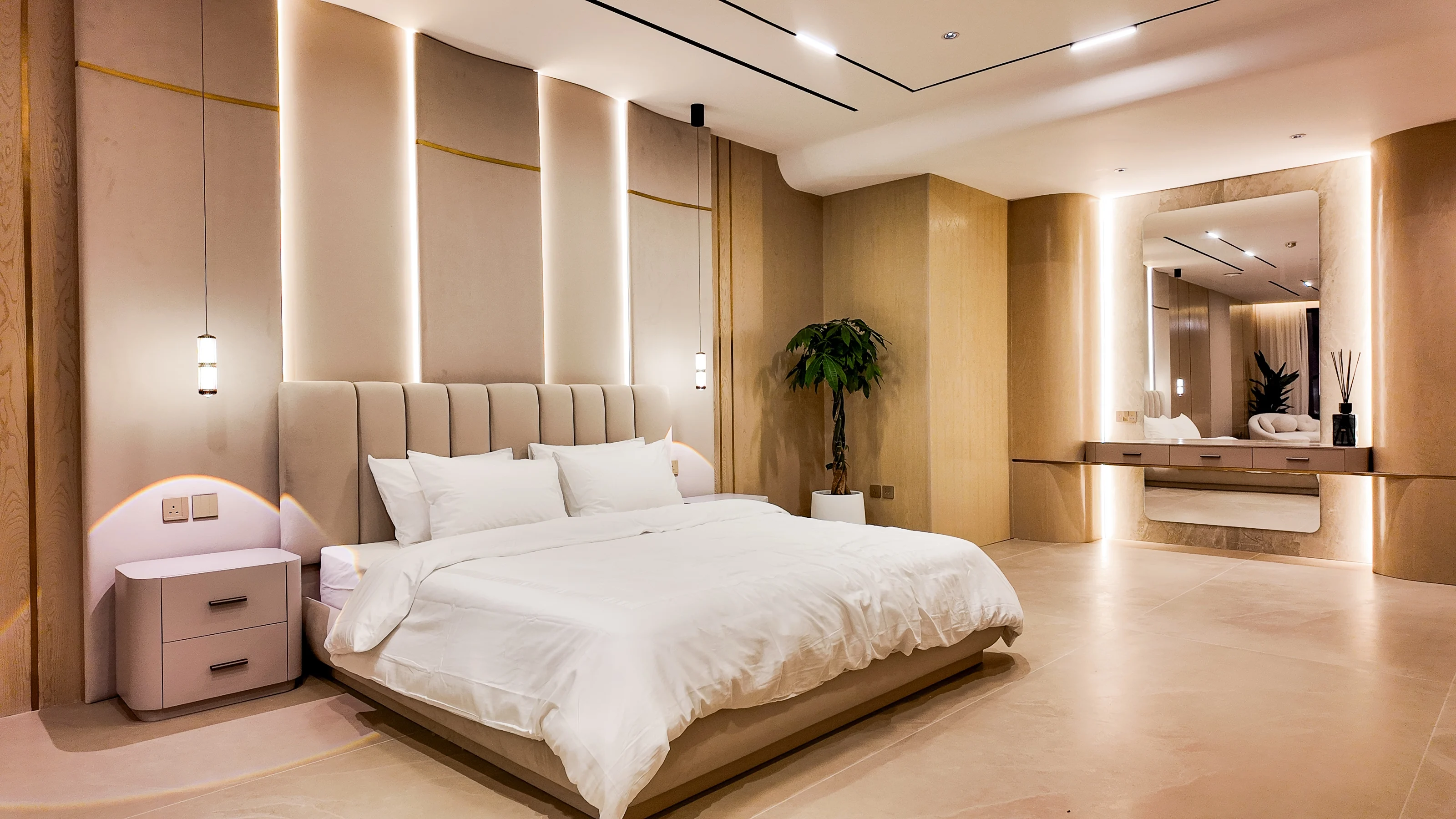 Master bedroom with a curved padded headboard, warm timber panelling and a mirrored vanity
