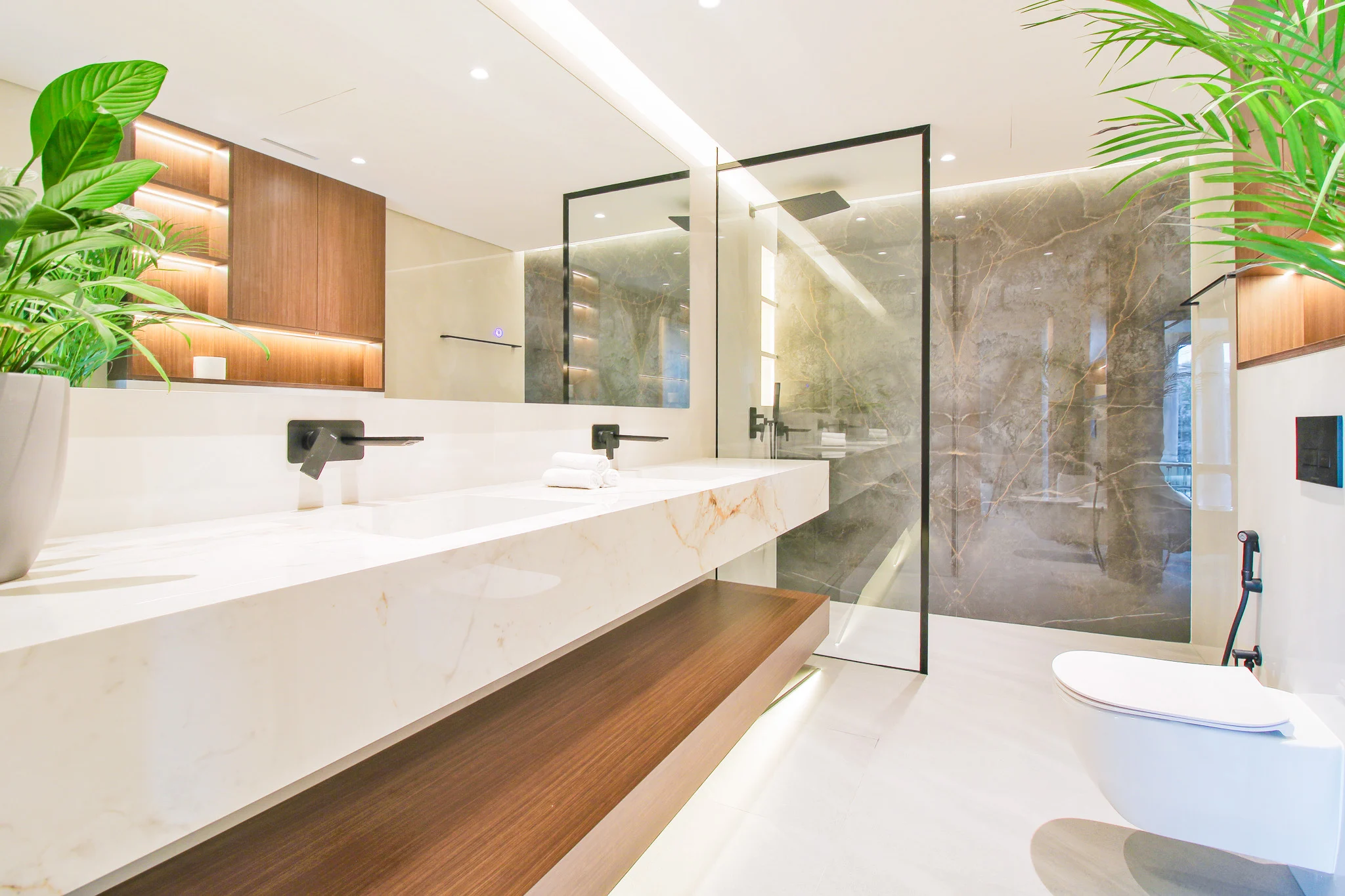 Ensuite bathroom with a book-matched white marble vanity, walnut shelf and a grey marble walk-in shower