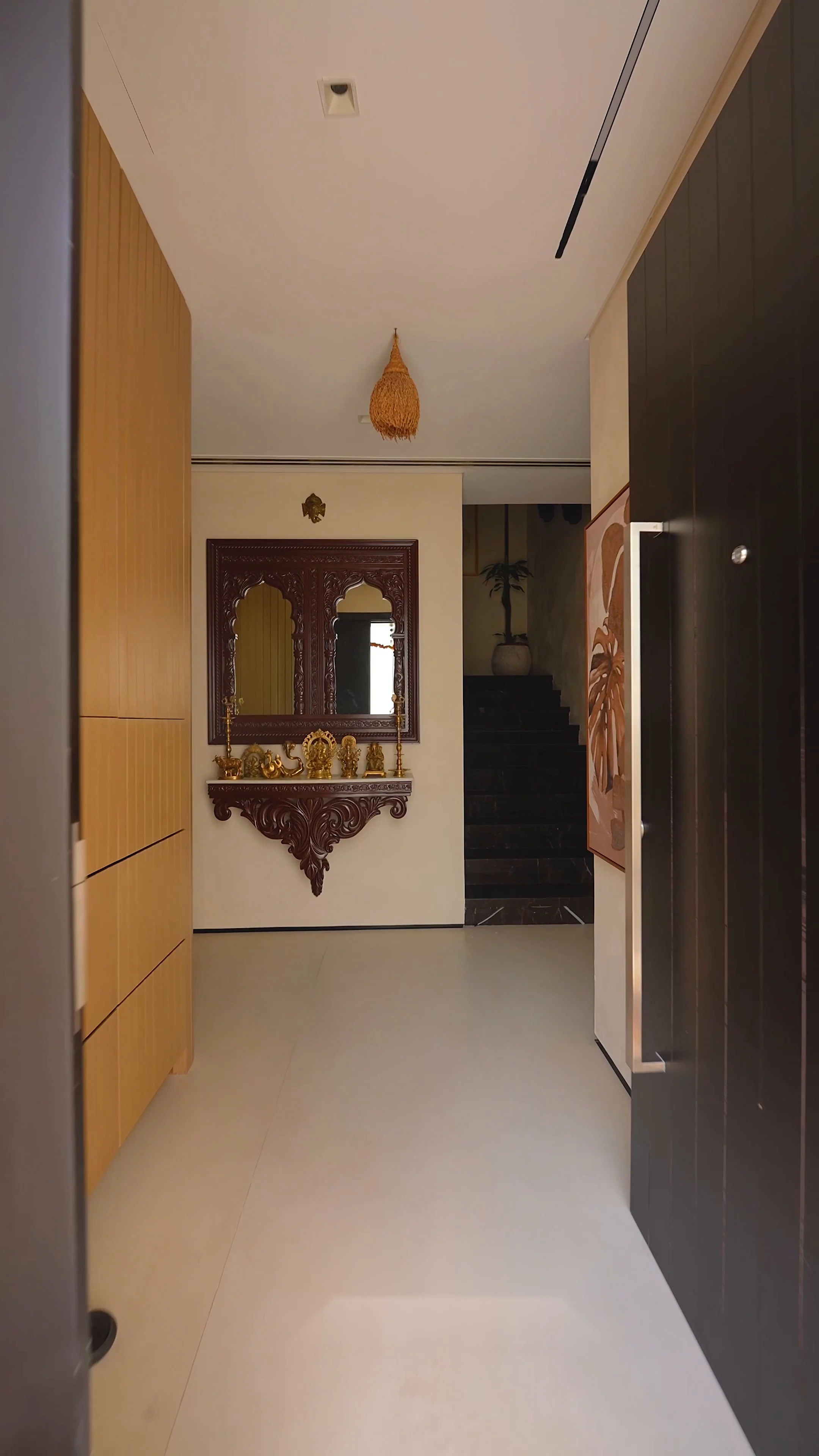 Entrance hallway with walnut cabinetry, a carved console beneath an antique mirror, and the staircase beyond