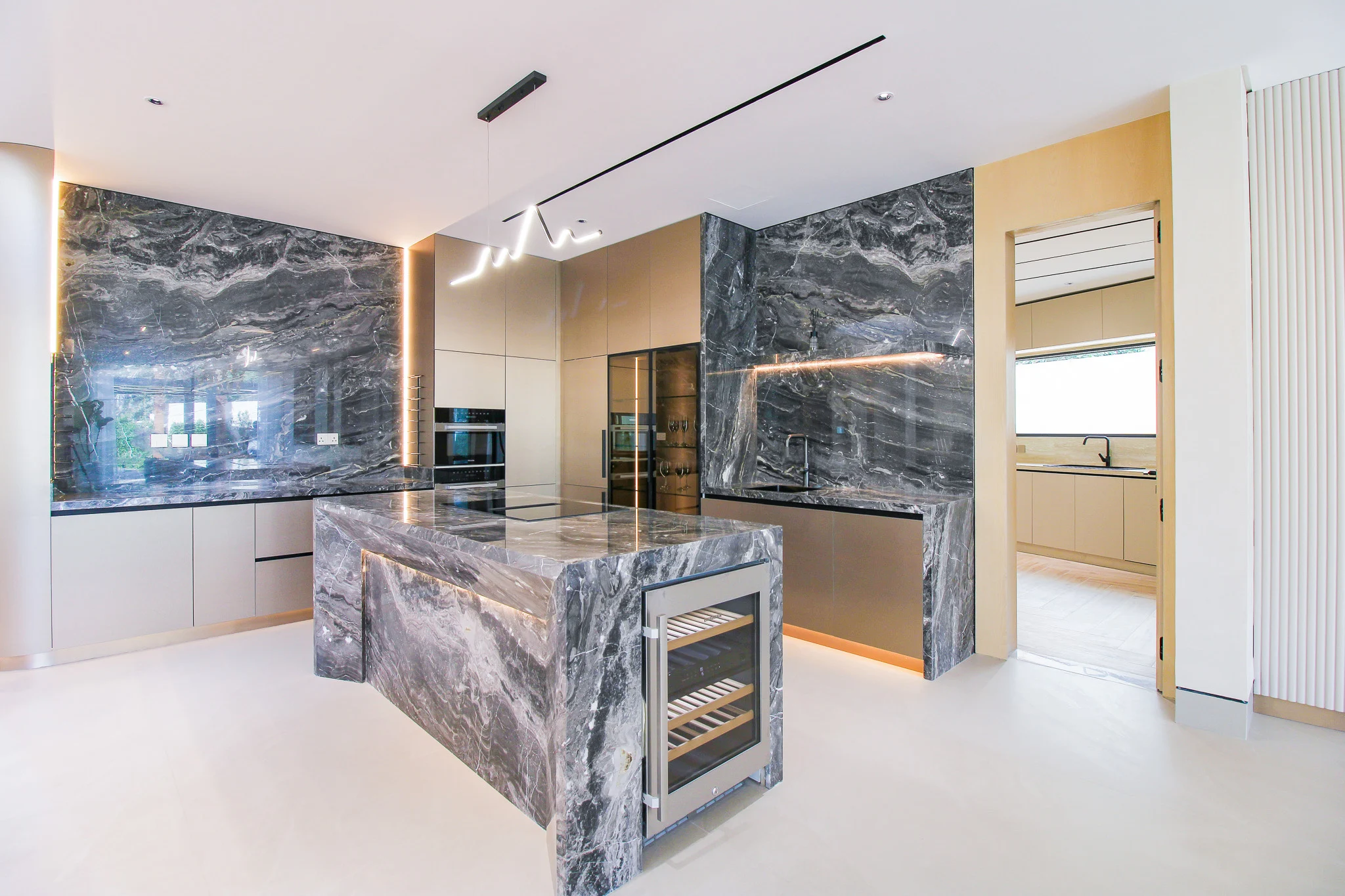 Kitchen in warm timber with dark marble counters and a lit stone island