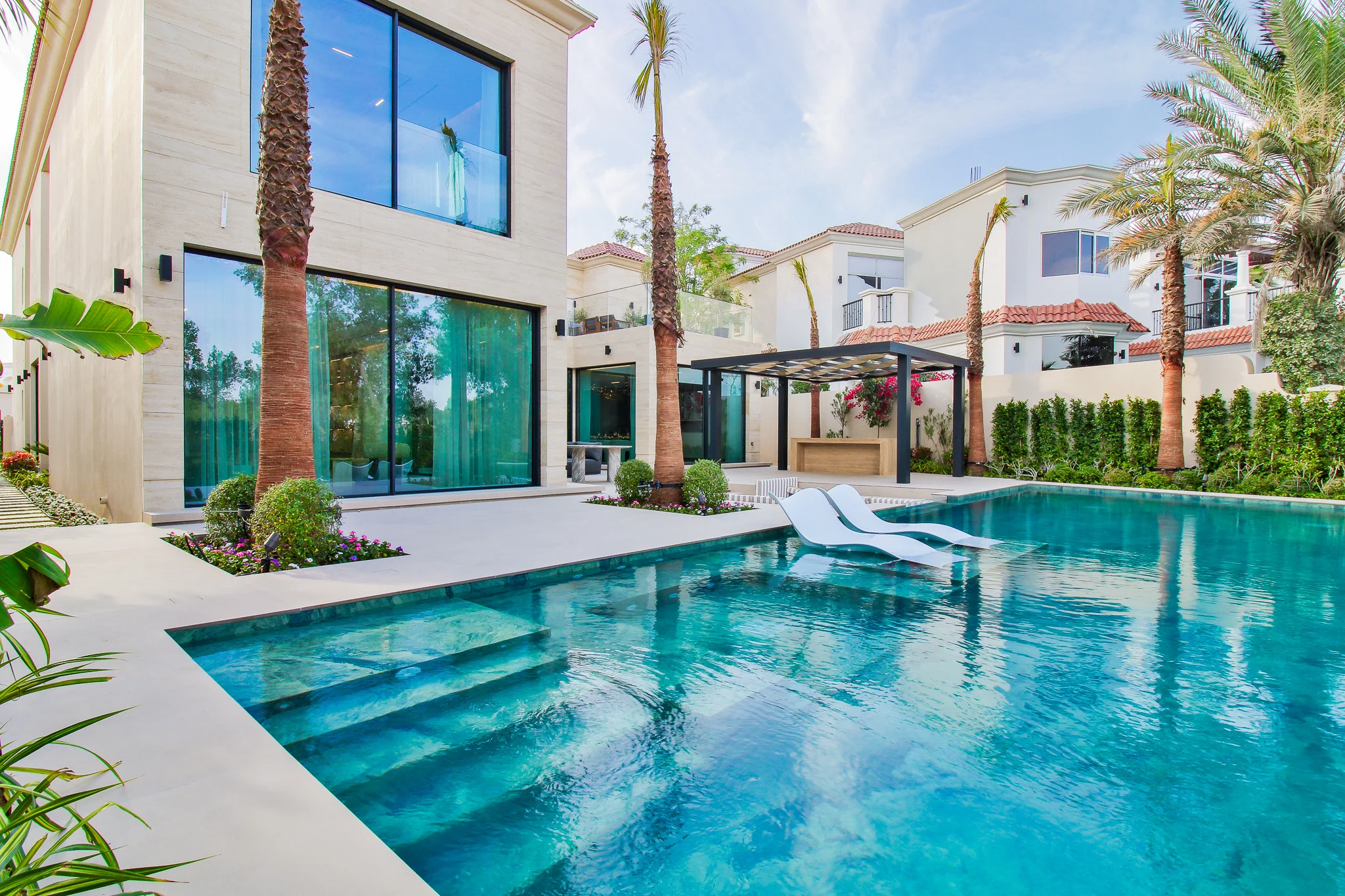 Infinity pool seen from the water's edge, palms and villa beyond